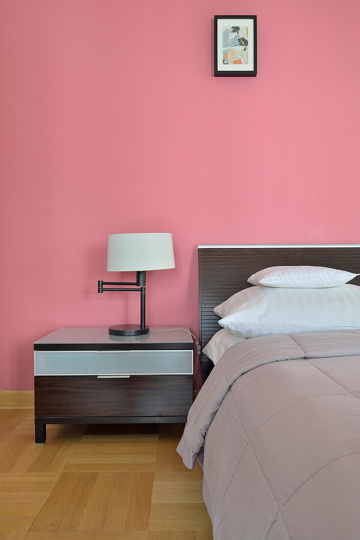 Modern bedroom with pink wall and dark bedside table