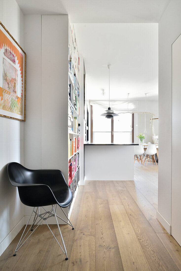 Hallway with wooden floor, designer chair and bookshelf