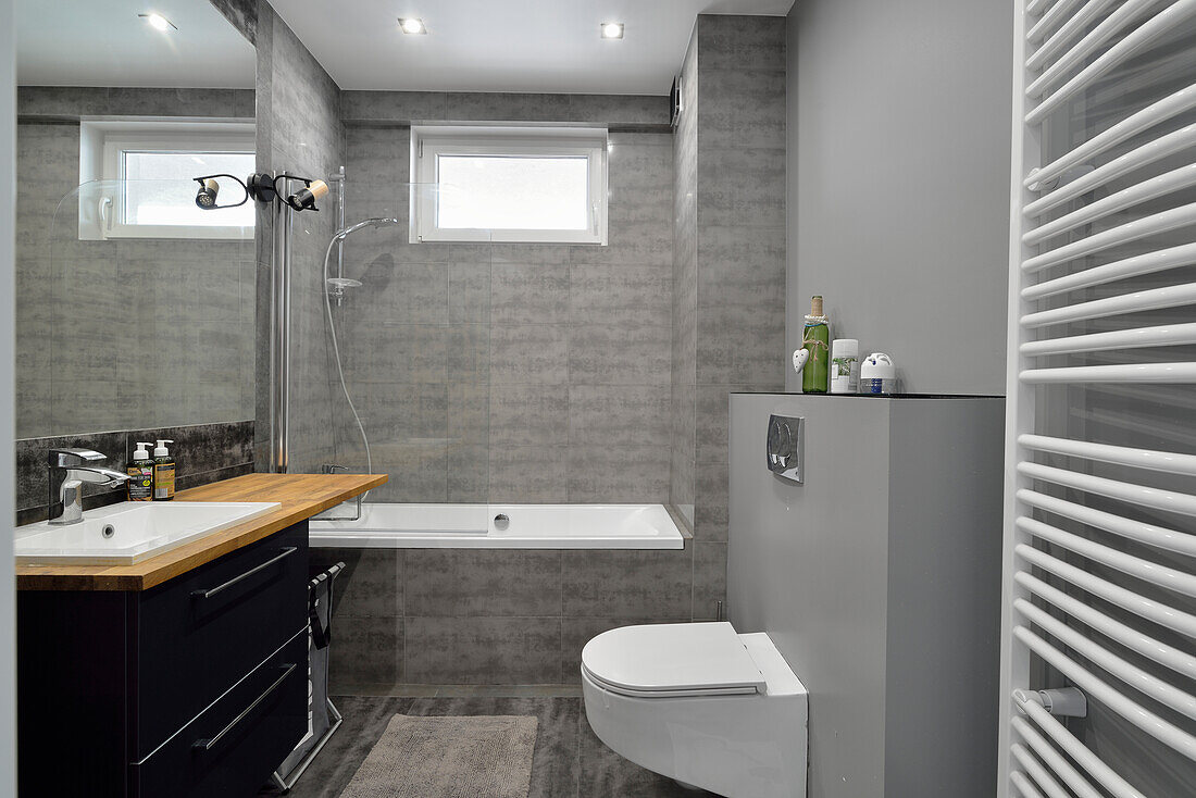 Modern bathroom with grey tiles and dark vanity unit