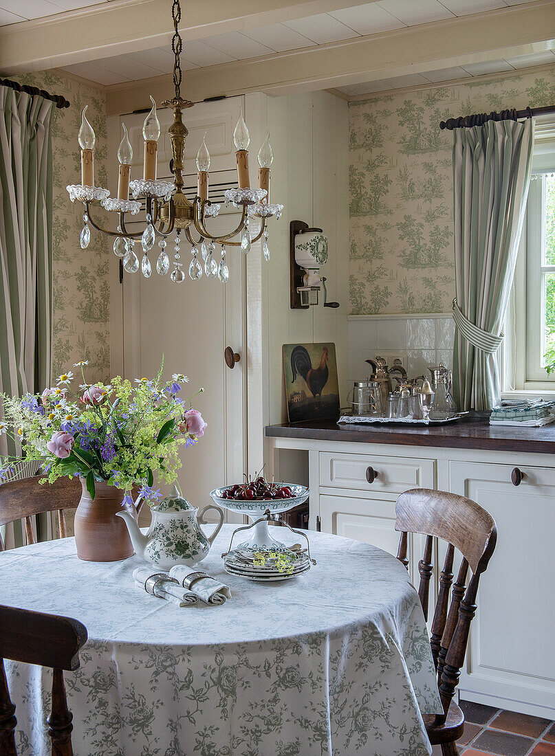 Country-style kitchen with chandelier and bouquet of flowers on round table