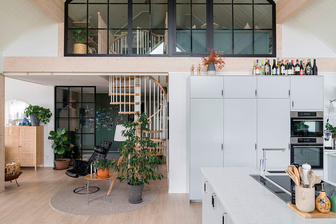 Open-plan living area with kitchen, spiral staircase and large windows