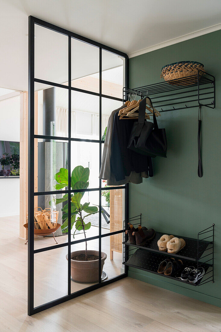 Black wardrobe and sliding glass door in the entrance area with green wall