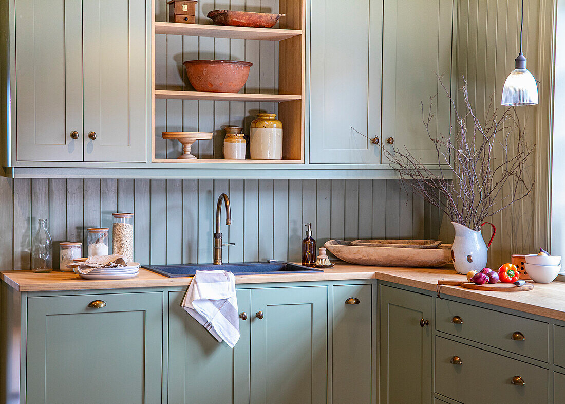 Country-style kitchen with mint green wooden cabinets and wooden worktop