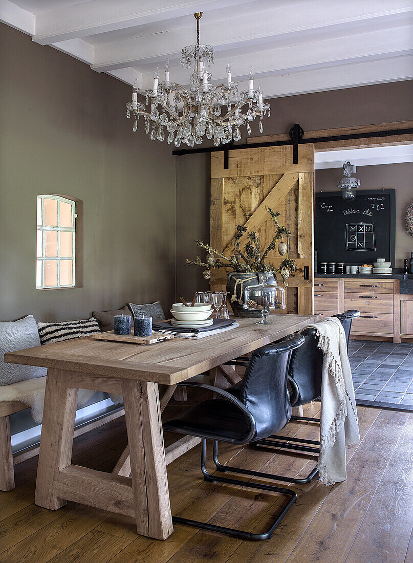 Wooden table with leather chairs and chandelier in dining room with sliding doors