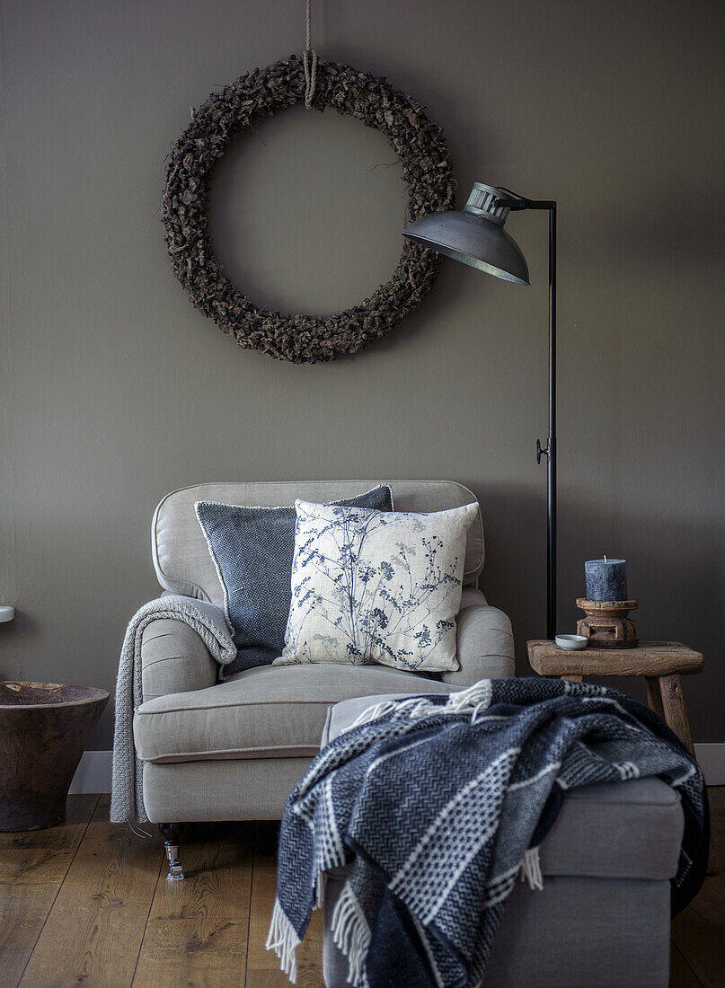 Armchair with cushions and blanket under the wall wreath in the living room