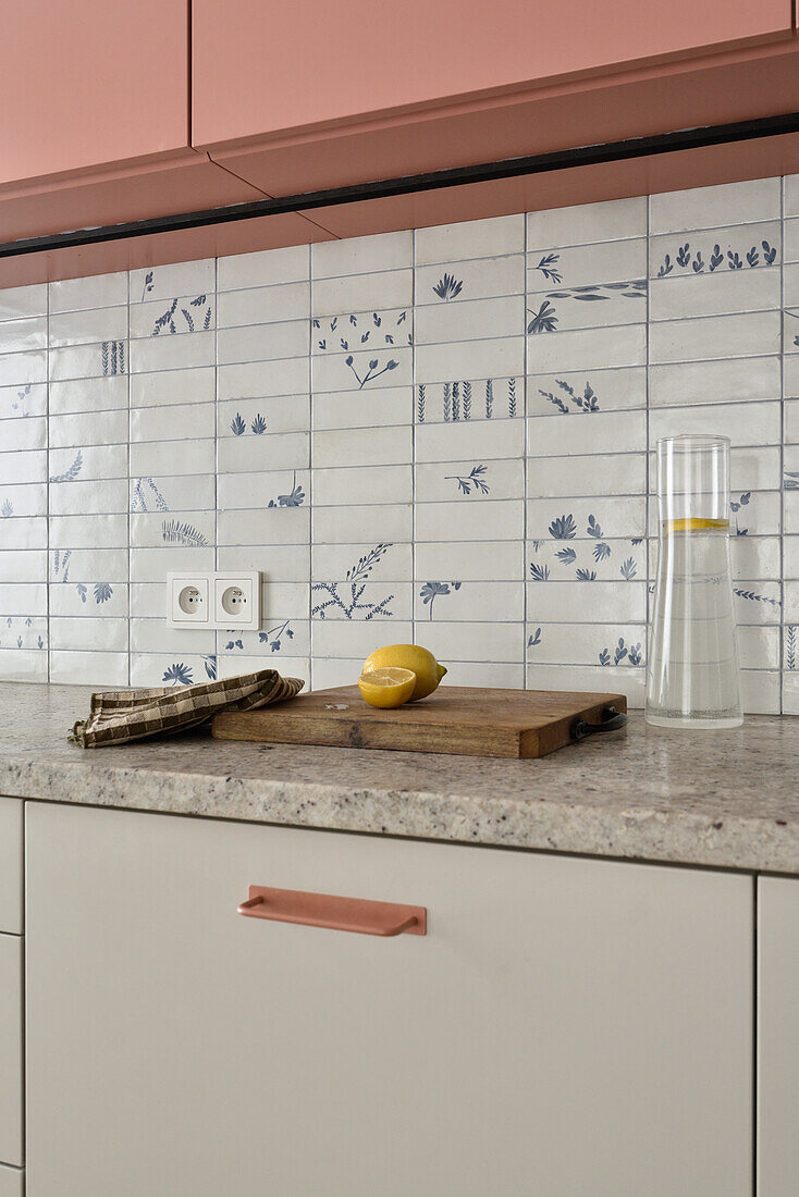 Kitchen with patterned tiled splashback and pink wall units