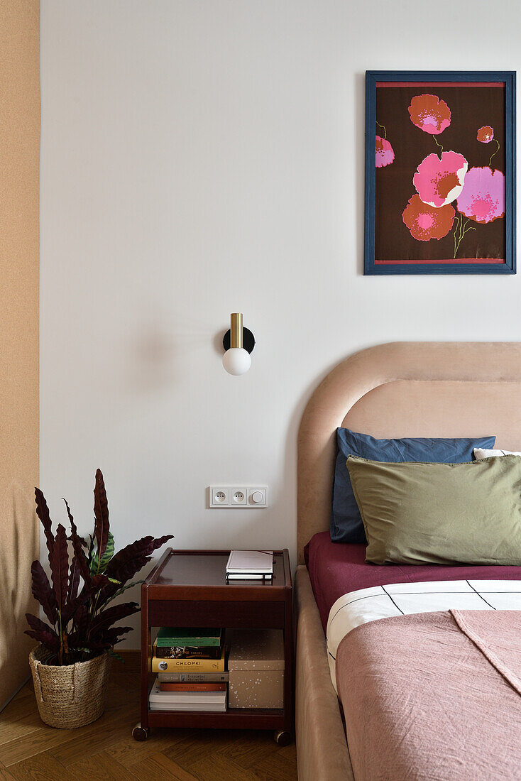 Bedroom with velvet bed, wooden bedside table and plant accent