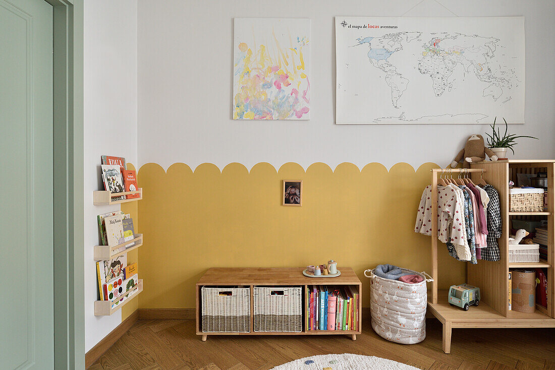 Children's room with yellow wall design, bookshelf and clothes rack