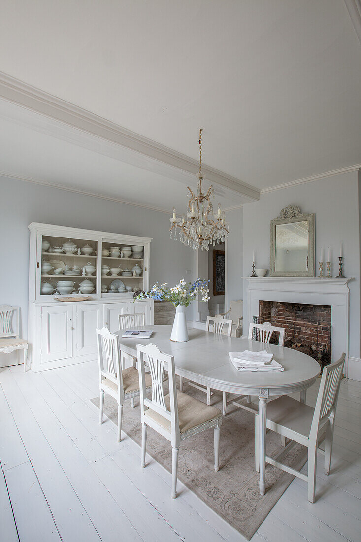 Dining room in shabby chic style with white dining table and crystal chandelier