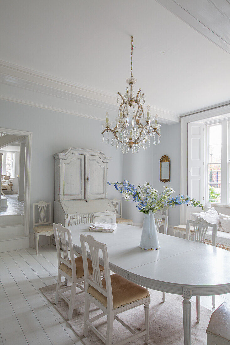 Country-style dining table with chandelier and white wooden cabinet