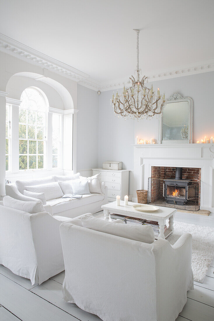 Bright living room with fireplace, white furniture and chandelier