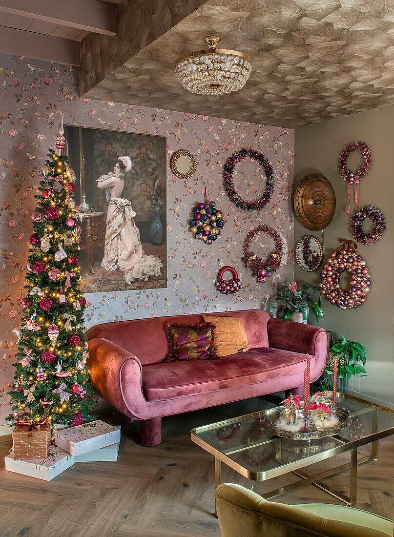 Living room with velvet sofa, Christmas tree and decorative wreaths on the wall