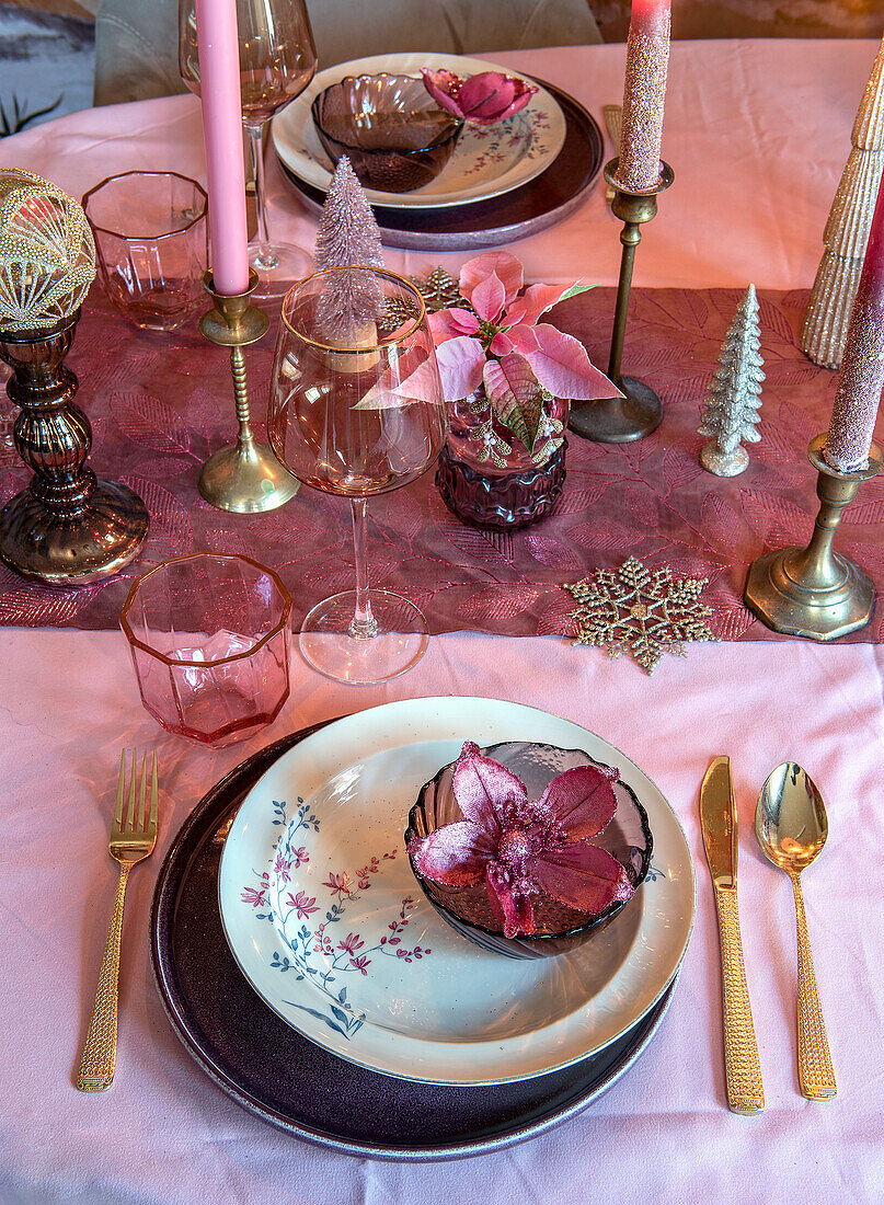 Festive table setting with pink accents, candles and decorative fir trees