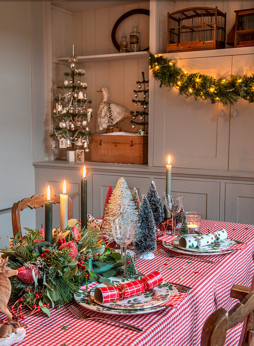 Festlich gedeckter Tisch mit Weihnachtsdeko, Kerzen und Miniatur-Tannenbäumen