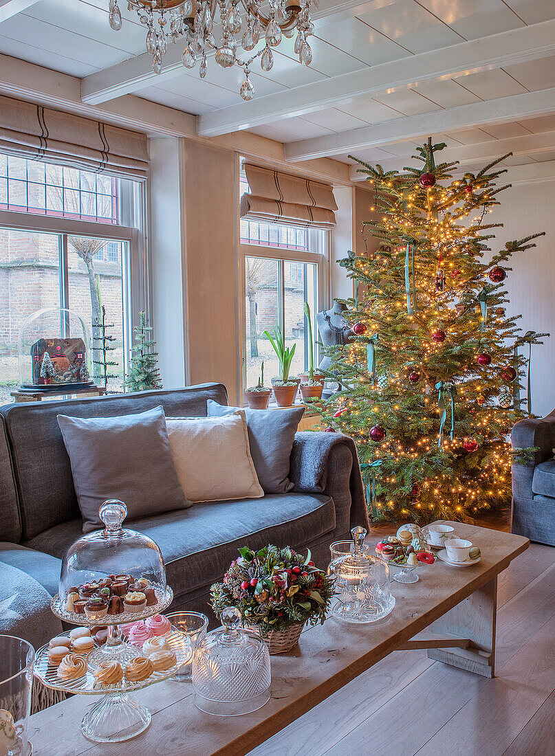 Wohnzimmer mit beleuchtetem Weihnachtsbaum und festlich gedecktem Couchtisch