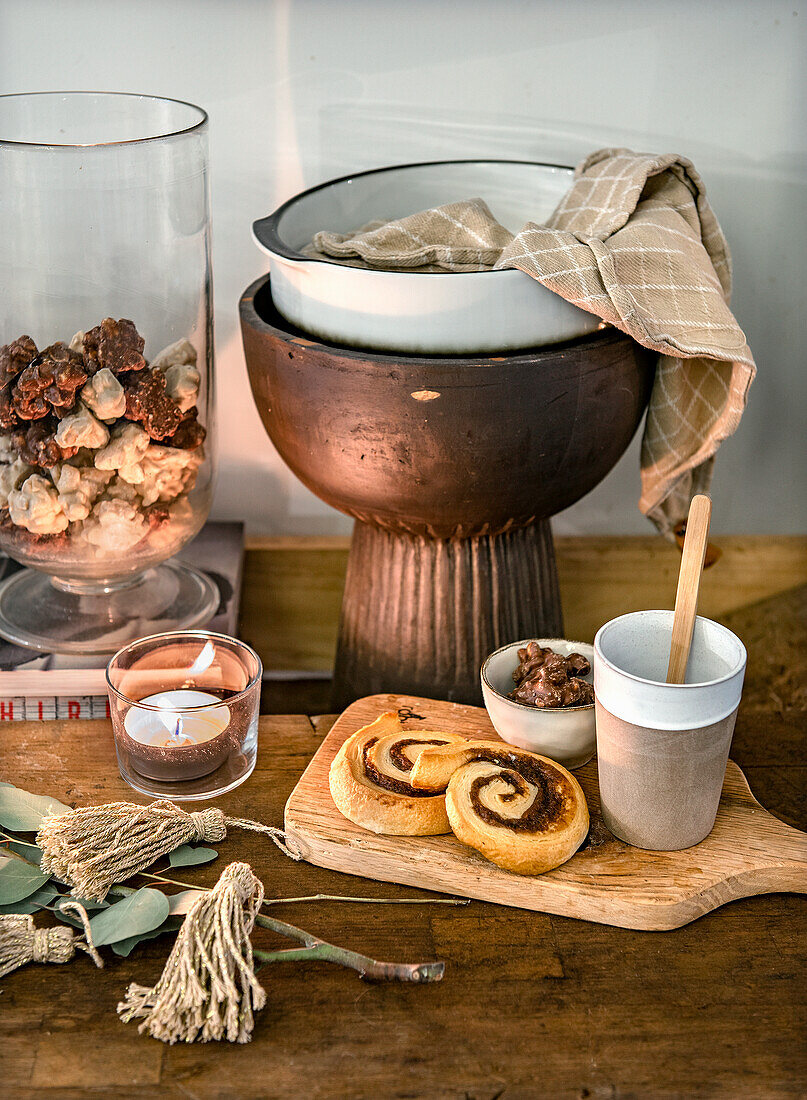 Holztisch mit Teelicht, Gebäck, Schalen und Naturdekoration