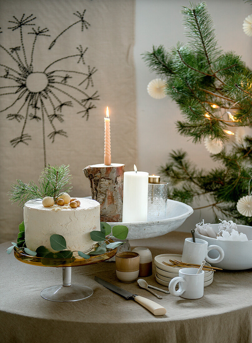 Weihnachtlich gedeckter Tisch mit Kuchen, Kerzen und Tannenzweigen