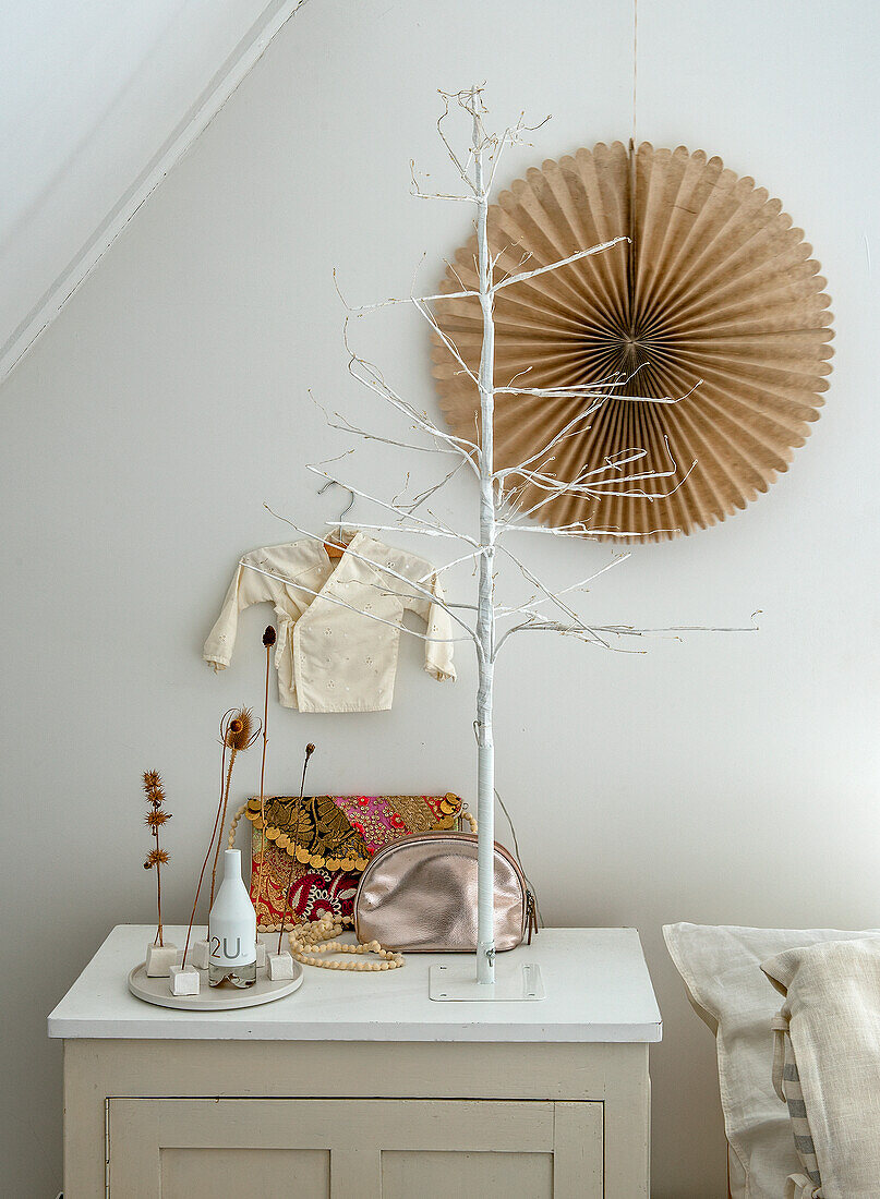 Dekorierter Nachttisch mit Lichterbaum und Trockenblumen, Papierrosette an der Wand