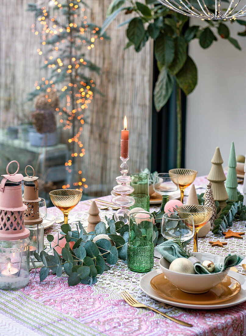 Festive table decorated for Christmas with eucalyptus, candles and golden accents