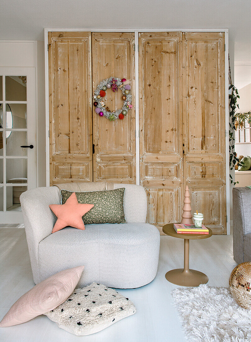 Modern armchair and side table in front of rustic wooden cupboards in the living room