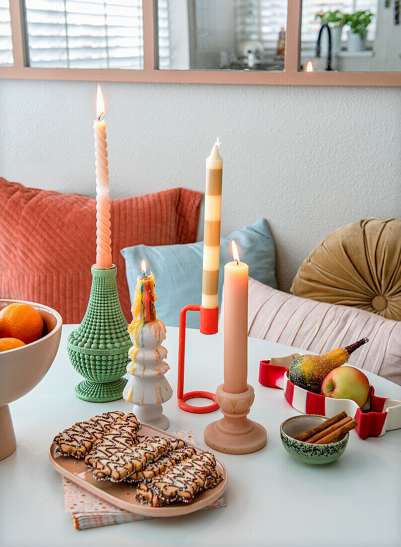 Candles and biscuits on table and colourful cushions on bench