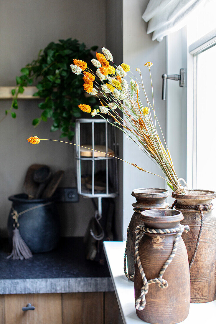 Rustic clay vases with dried flowers on a windowsill