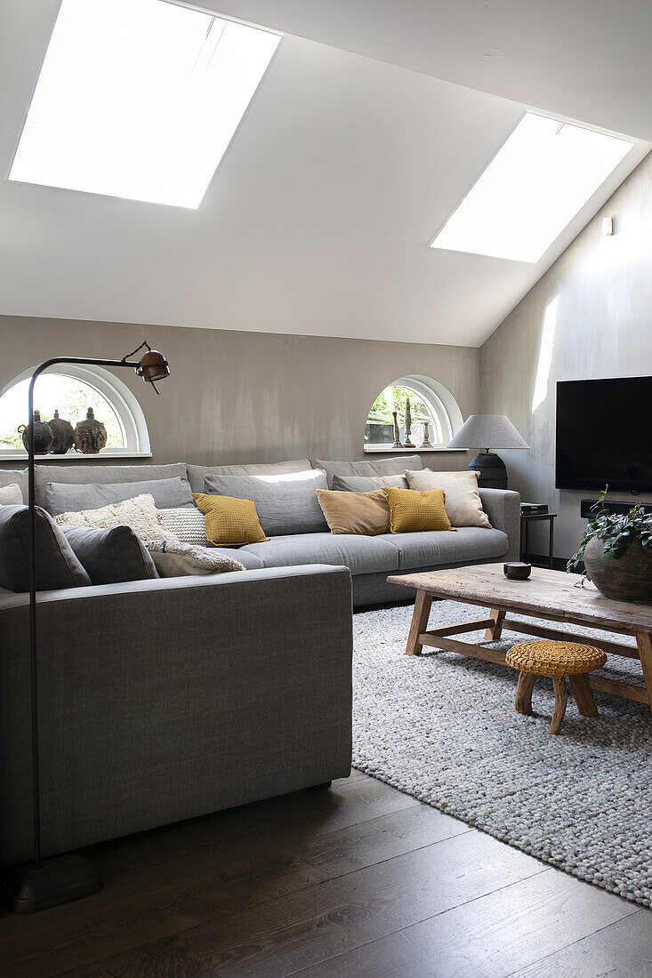 Living room with grey corner sofa and yellow cushions under skylights