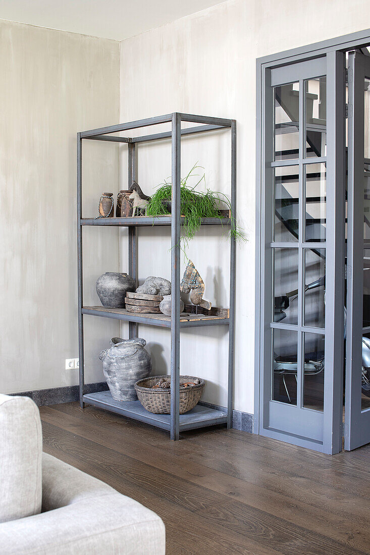 Metal shelf with decorative ceramics and plants in modern living room