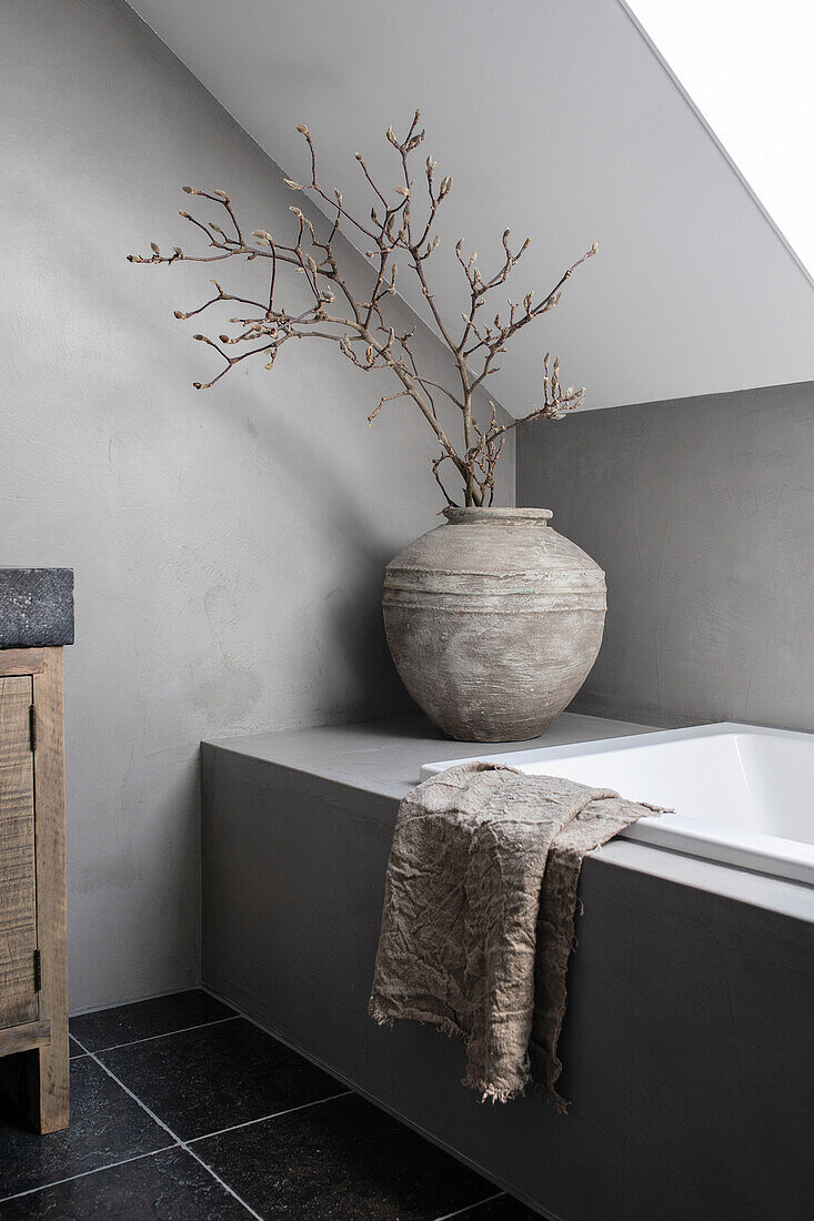 Simple bathroom decoration with large vase on bathtub rim