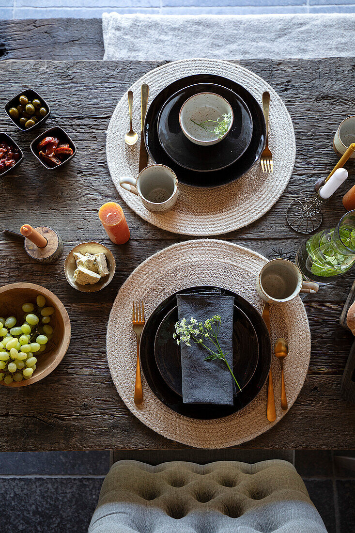 Gedeckter Tisch mit schwarzen Tellern und goldenem Besteck