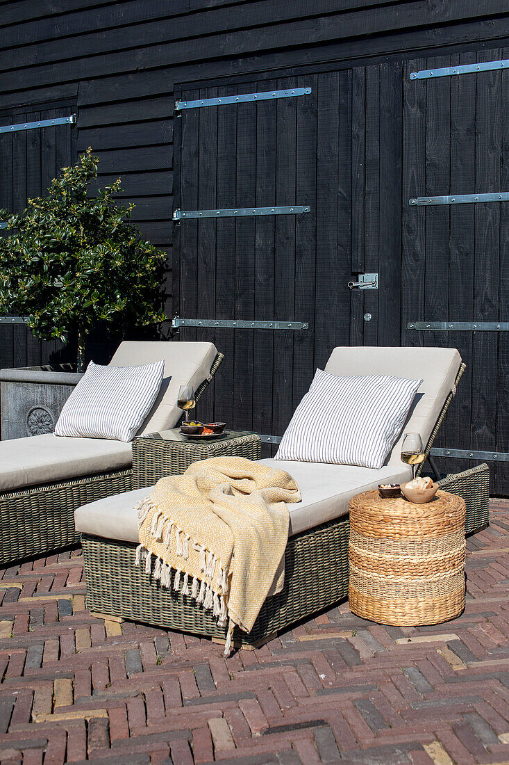 Sun loungers with cushions and blanket on a terrace made of brick slabs