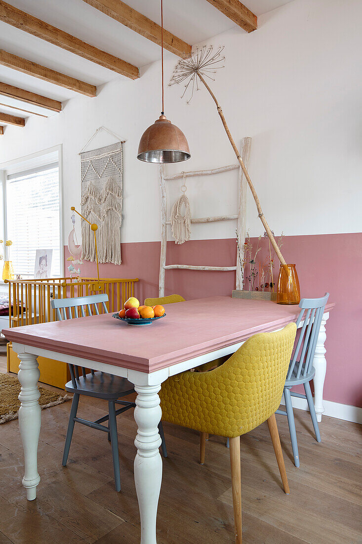 Esstisch mit rosa Tischplatte, Holzbalkendecke und Wand in Weiß und Rosa