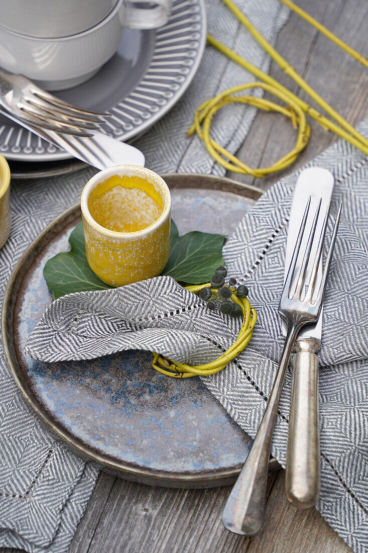 Table setting with rustic plates and silver cutlery, napkin ring made from twigs with ivy berries