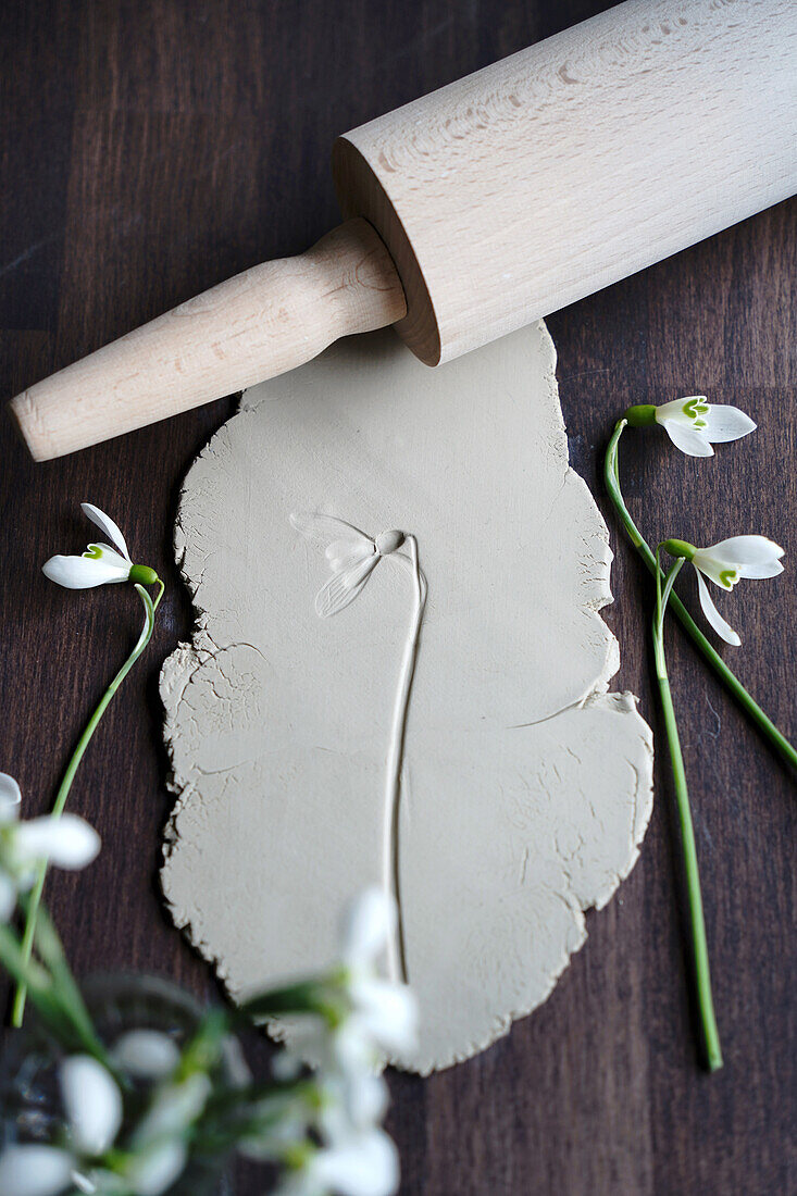 Rolled out clay with flower print, rolling pin and snowdrops