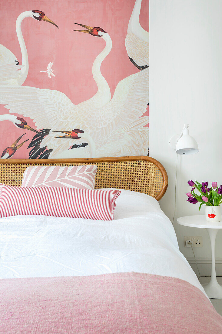 Bedroom with rattan bed, pink wallpaper with heron print and tulip bouquet