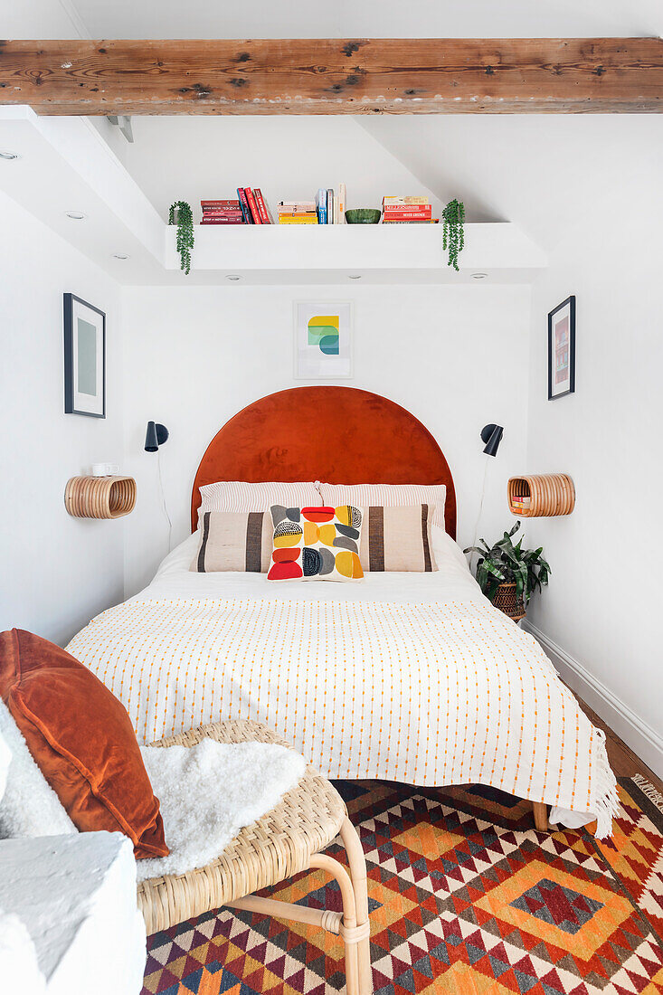 Small bedroom with red bed headboard and patterned carpet