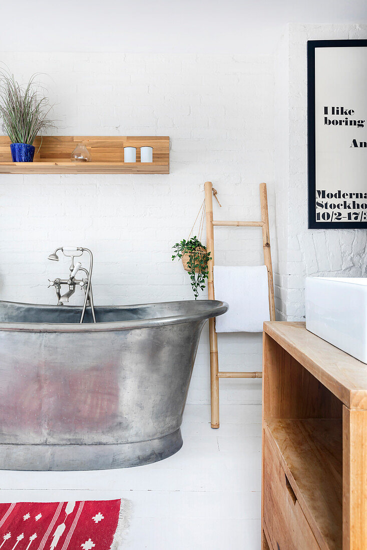 Freestanding metal bath in modern bathroom with white walls and wooden elements