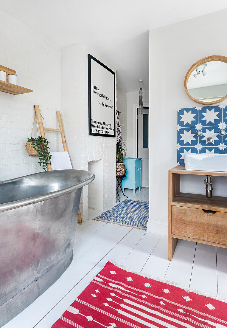 Bathroom with freestanding metal bathtub, blue and white star tiles and red carpet with white pattern