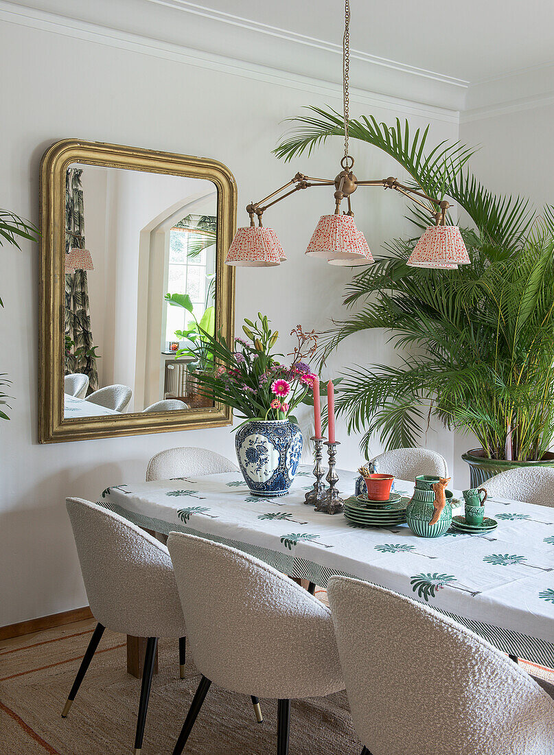 Dining room with large mirror, plants and table set with candles and crockery