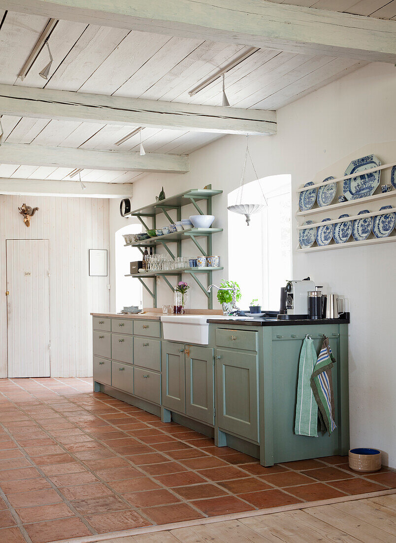 Country-style kitchen with green cupboards and open shelves