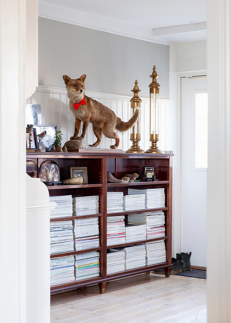 Shelf with stacked magazines and stuffed fox in the entrance area