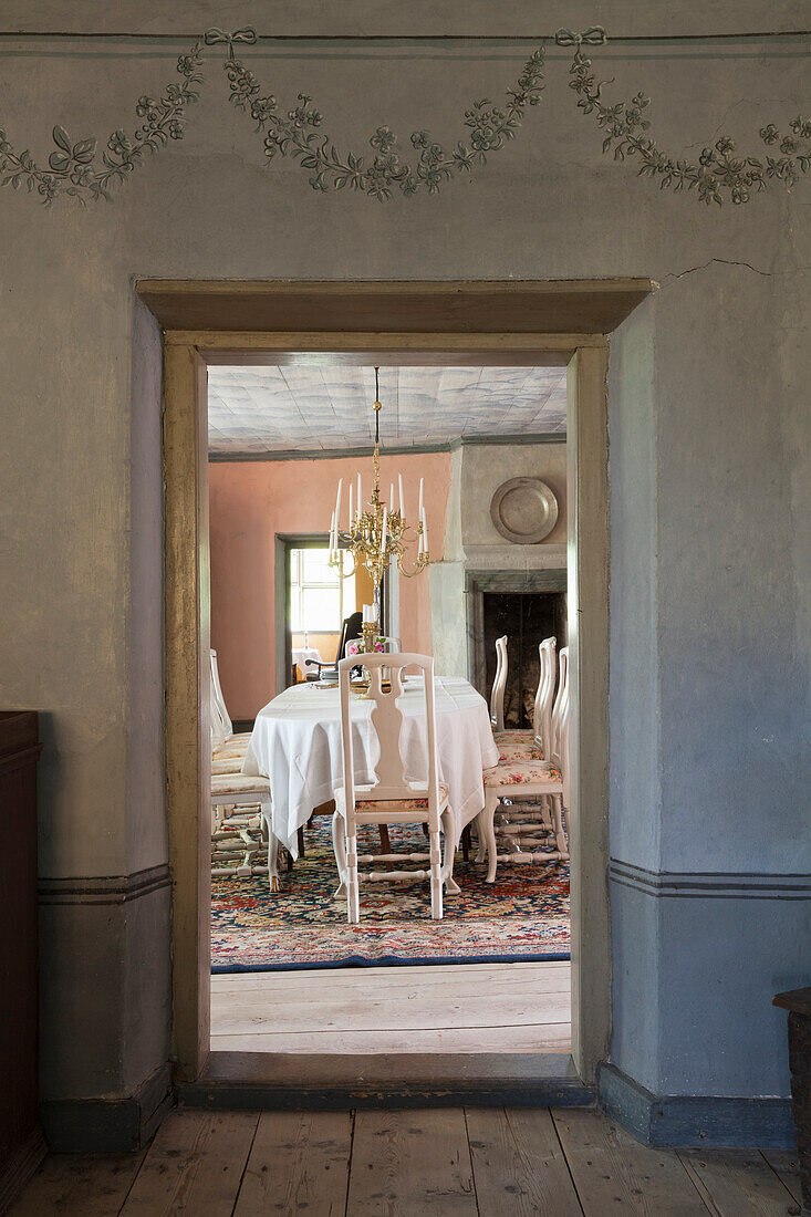 Blick in Esszimmer mit weißer Tischdecke und antiken Holzstühlen