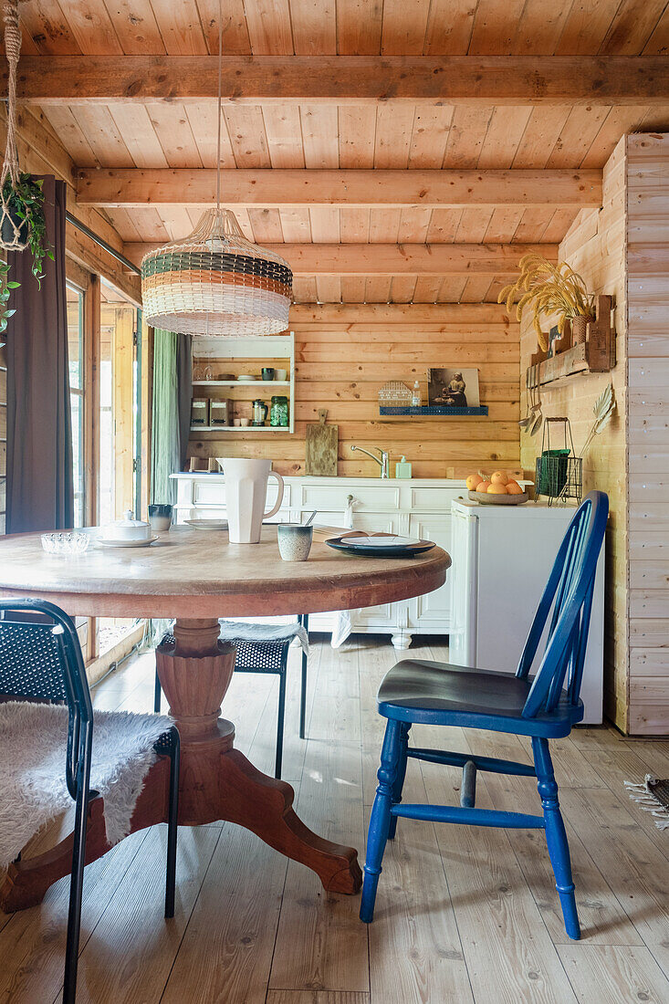 Essbereich in Holzhütte mit rundem Tisch und blauem Stuhl