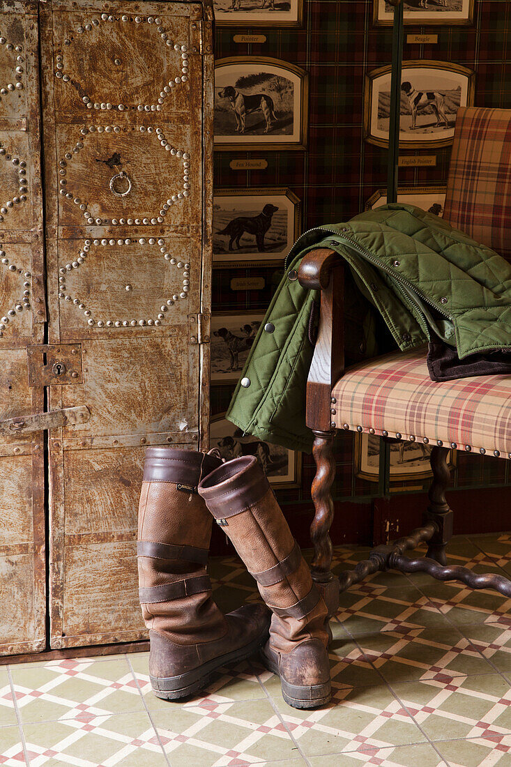 Rustic cloakroom area with checkered armchair, boots and green coat