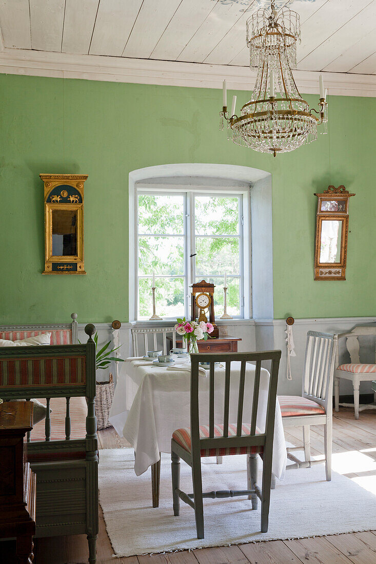 Dining room with antique furniture, chandelier and green-painted walls