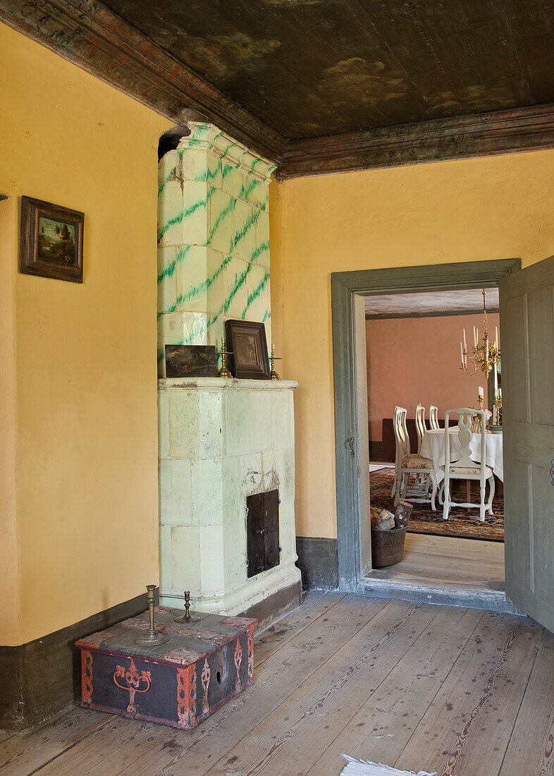 Antique living room with green and white tiled stove and view into the dining room