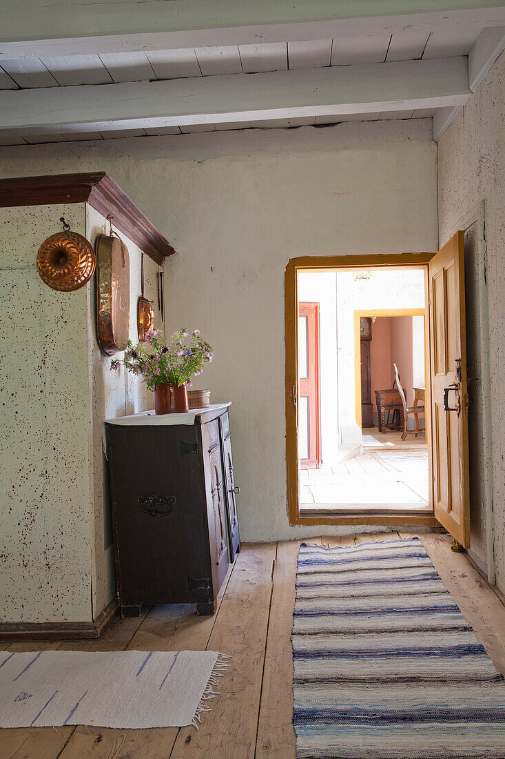 Altmodischer Flur mit Holzmöbeln und gestreiftem Läufer mit Blick in sonniges Zimmer