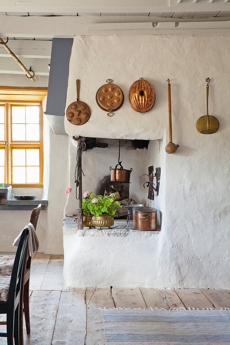 Historic kitchen with copper crockery on rustic wall and open fireplace