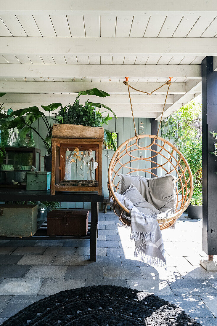 Hängesessel aus Rattan auf überdachter Terrasse mit Pflanzen