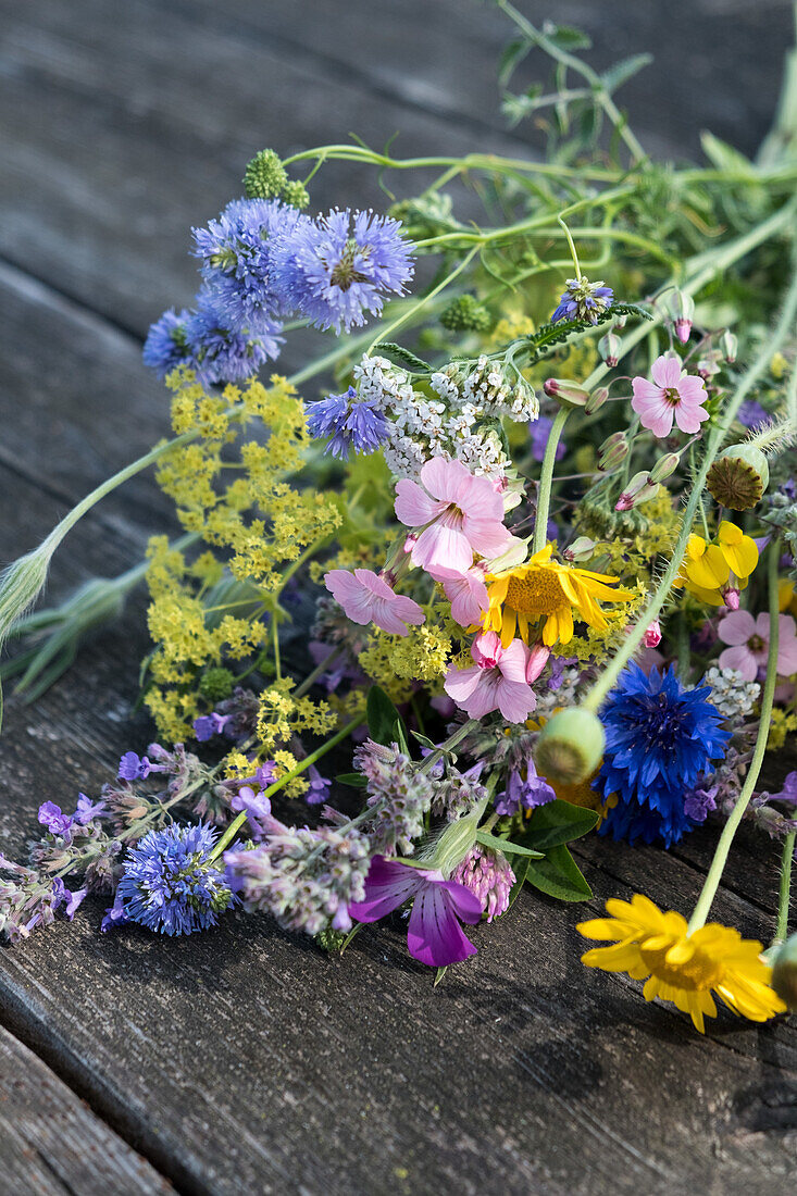 Bunter Wildblumenstrauß aus verschiedenen Sommerblumen auf Holztisch